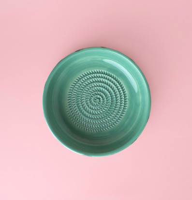 Foto av jadegrön keramisk rivskål på rosa bakgrund