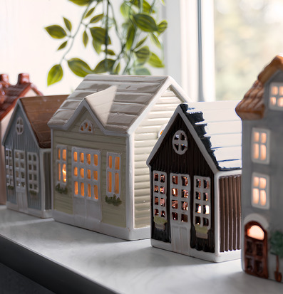 Foto av keramikljuslyktor som små hus på fönsterbänk