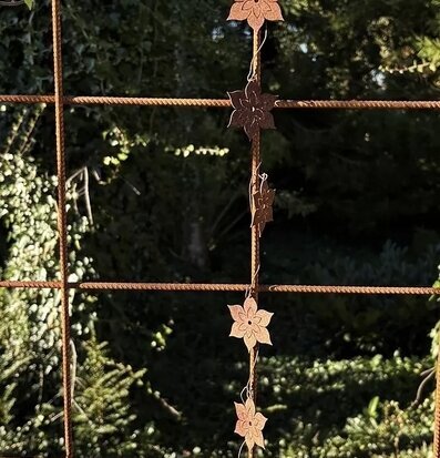 Foto: Rostig metallgirlang med blommor på armeringsnät