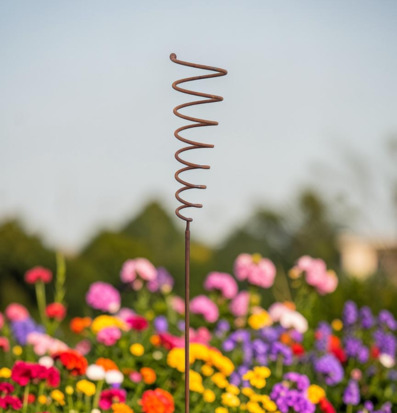 Foto av rostfärgad spiral på trädgårdsspjut i rabatt