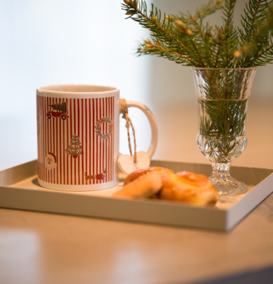 Bild på julmugg med röda ränder, saffransbullar, gran
