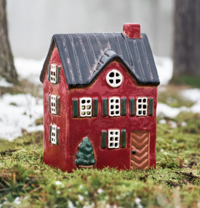 Foto: Röd husformad ljuslykta på mossa och snömark