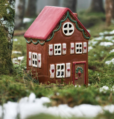 Foto av keramiskt hus i mossig skog med snöfläckar