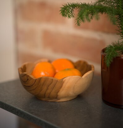 Foto av teakskål med citrus på köksbänk, tegelvägg