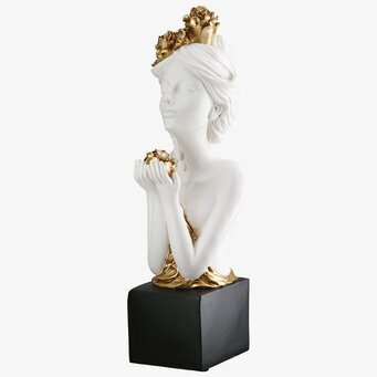 Foto: Vit kvinnofigur med gulddetaljer på sockel
