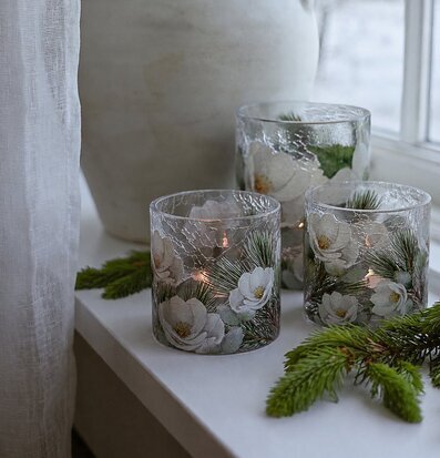 Foto: Tända glaslyktor med vinterblommor i fönster