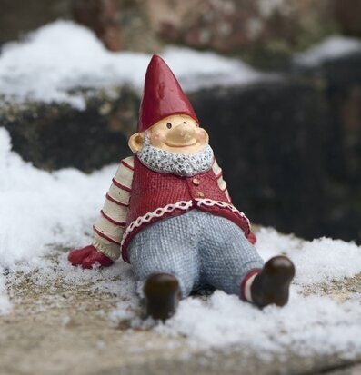 Foto: Sittande tomtefigur i snö utomhus vintermiljö