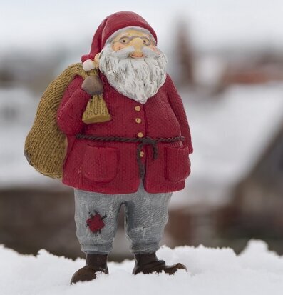 Foto: Tomtefigur i snö med säck, skägg och luva