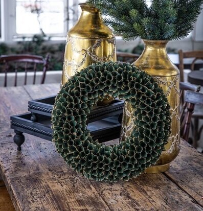 Foto grön glitterkrans på bord med guldvaser julpynt