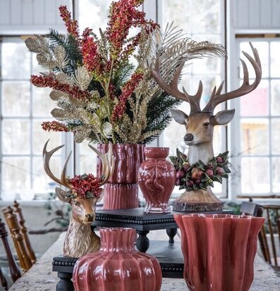 Foto: Hjortbyster med blomkrans och röda vaser i fönsterljus