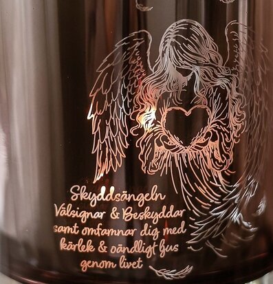 Foto: Mörk glaslykta med ängelgravyr och ljusglöd