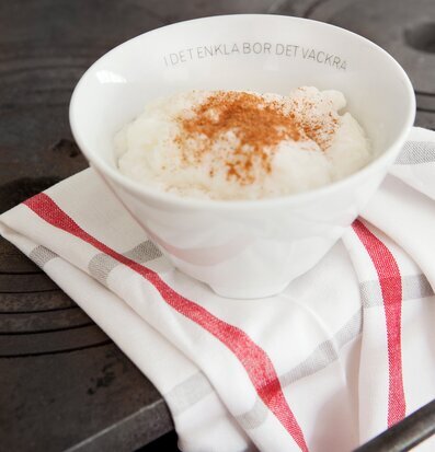 Bild av stilren skål på rustik spis med gröt och kanel