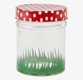 Bild av glasburk med dekorativt lock och gräsmönster