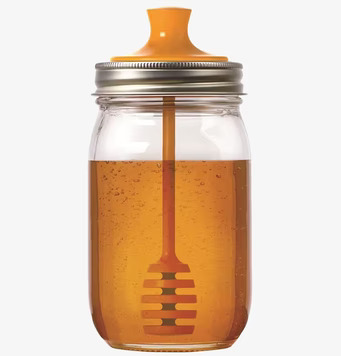 Bild av glasburk med honung och orange honey dipper