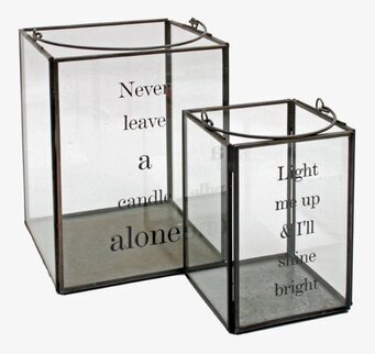 Bild av två ljuslyktor i glas och metall med texter