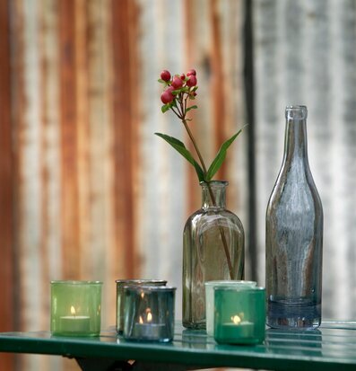 Bild av stilrena glasflaskor och ljushållare i grönt