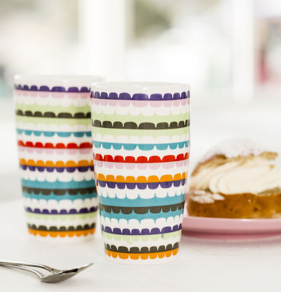 Bild av färgglada lattemuggar och bakelse i ljus miljö