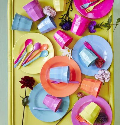 Bild av färgglada tallrikar och bestick på gul bakgrund
