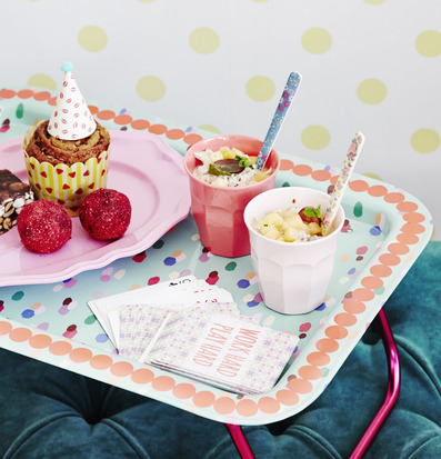 Bild av livlig sängbricka med färgglada mönster och fika