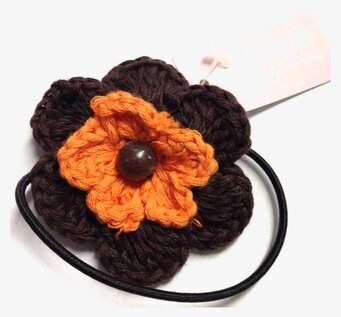 Bild på dekorativ hårsnodd med virkad blomdesign