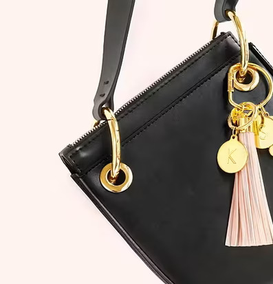 Foto av stilren väska med gyllene detaljer och tofs