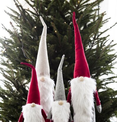 Bild av tomtefigurer framför en ståtlig julgran