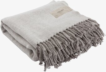 Bild av ljusgrå pläd med fransar och minimalistisk stil