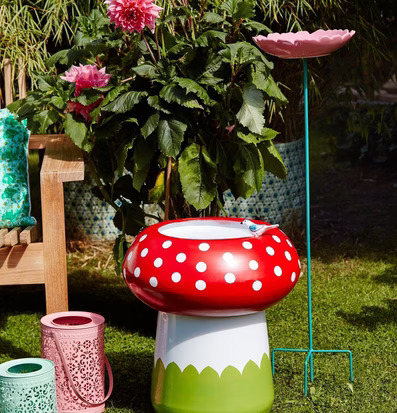 Bild av livfull trädgårdsscen med fågelbad och lyktor