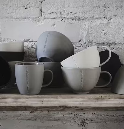 Foto: Stengods i grått på rustik hylla med tegelvägg