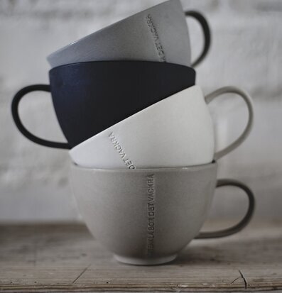 Foto av fyra harmoniskt staplade tekoppar mot tegelvägg